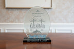 Glass trophy with engraved design of a city skyline, bridge, and whale, on a white background.