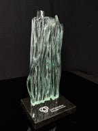 10 inch tall Canadian handcrafted Kiln Formed casted Glass waterfall award statue, that sits on top of a granite natural stone base with silver etching on top. the award stands in front of a black studio background