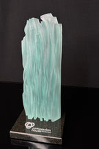 8 inch tall Canadian handcrafted Kiln Formed casted frosted glass frozen waterfall sculpture award, that sits on top of a polished granite natural stone base with a logo etched on top. the award stands in front of a black studio background