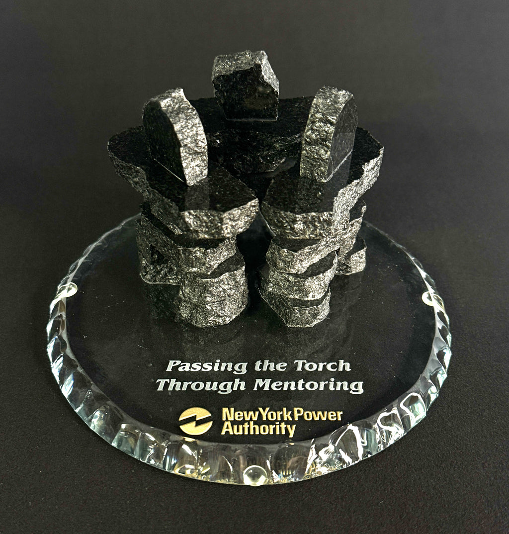 3 Handcrafted 2.5 inch tall Chipped edge black polished granite inukshuks stand in a friendship circle on top of a clear glass base with etching on top, standing in front of a black studio background 