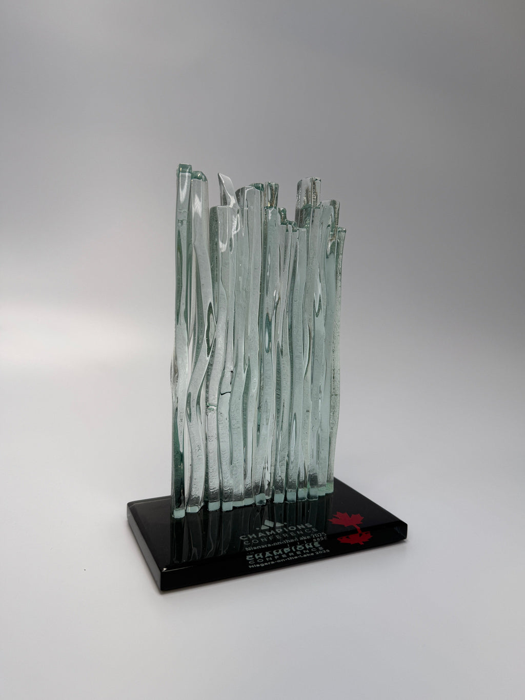 Glass waterfall sculpture on a black base with a gray background