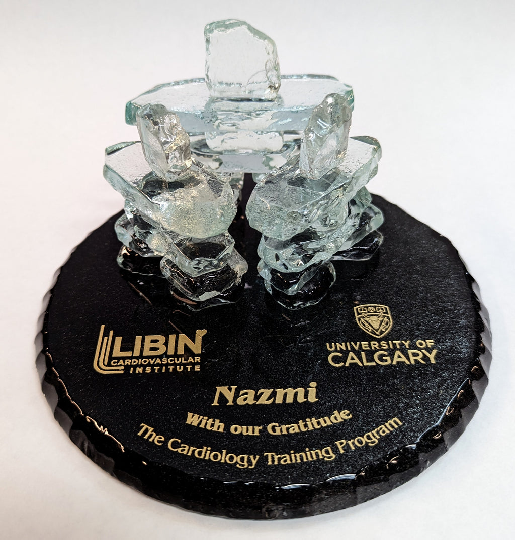 3 Clear Glass Inukshuks, Standing in a triangle formation. on top of a Black Painted glass base, with Gold etching Stating "Libin Cardiovascular institute" "University of Calgary" and "With our gratitude The Cardiology training program"