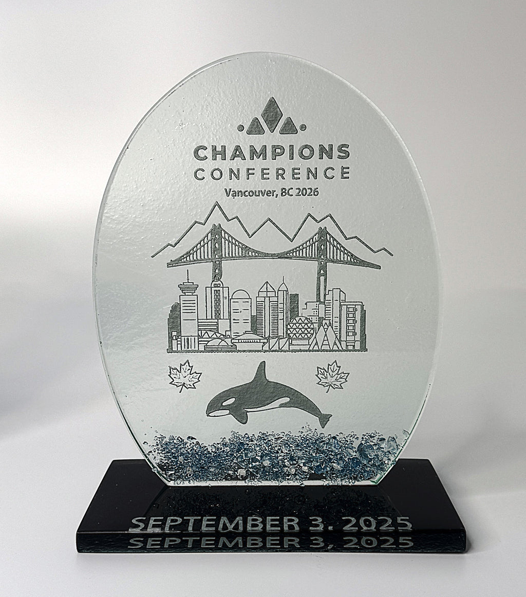 Glass award trophy with engraved design of a city skyline, bridge, and whale, on a black base.